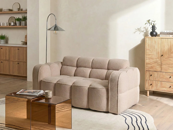 Beige sofa in a living room with wooden coffee table and shelves.