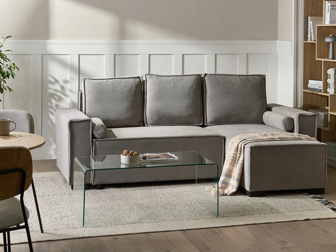 Gray sectional sofa in a living room setting with a glass coffee table.
