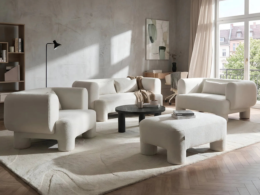 Modern living room with white furniture and large windows.