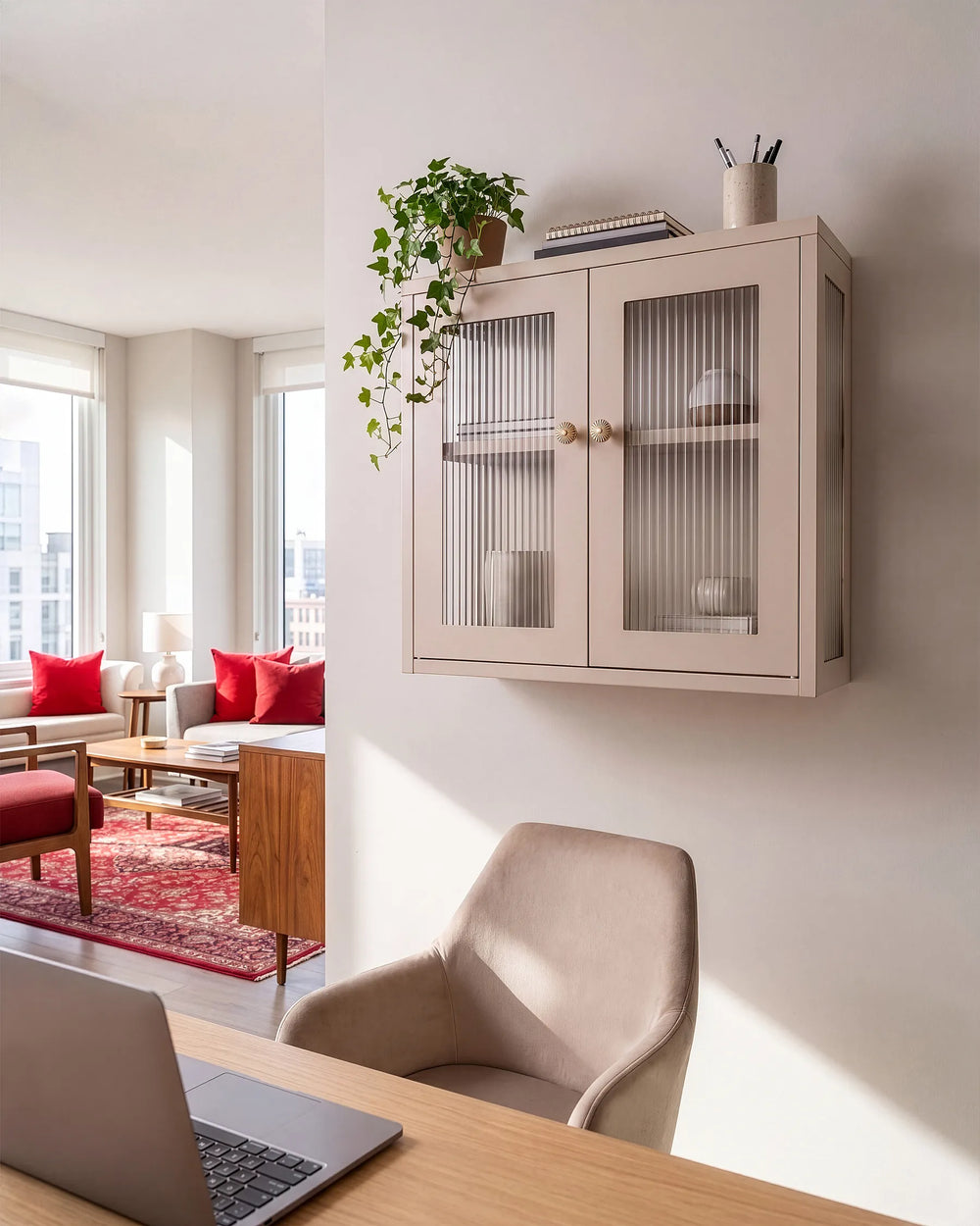 A light beige wall-mounted cabinet with two ribbed glass doors and gold knobs, styled in a modern loft apartment above a desk with a laptop and chair.