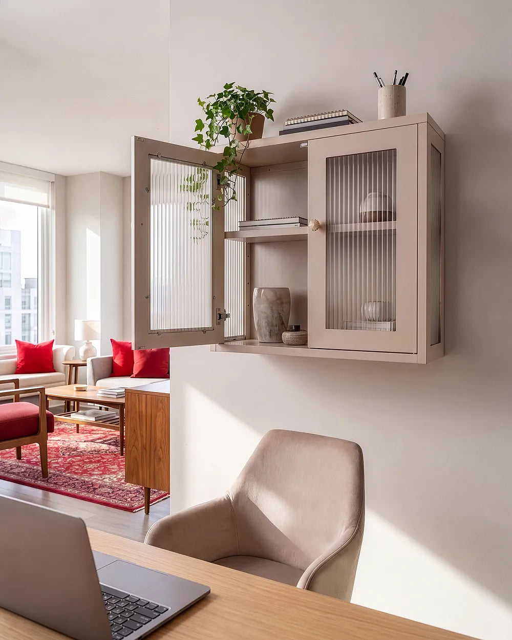 A wall-mounted light beige cabinet with frosted glass doors and open shelves, styled in a modern living space above a desk with a laptop and chair.