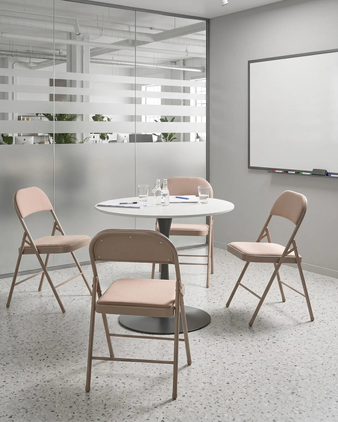 Round table with four folding chairs in a modern office setting