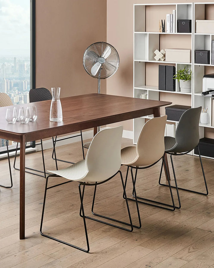 Dining area with a wooden table and modern chairs in a well-lit room.