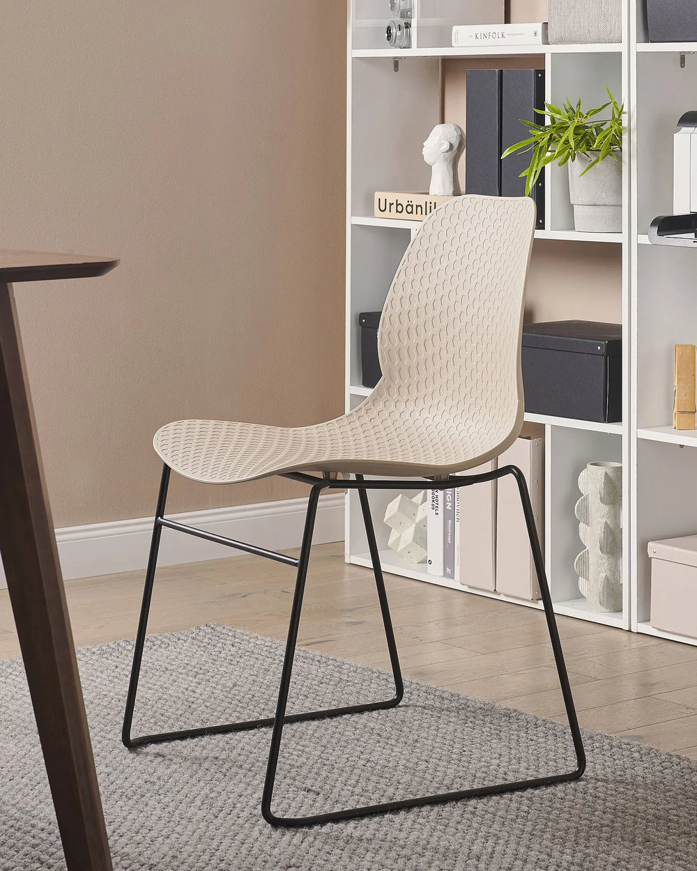 Beige chair with black legs in a room with shelves and decor