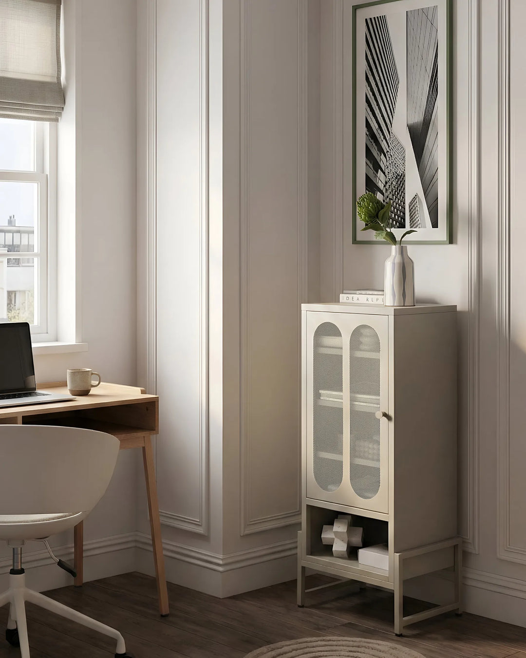 A tall, narrow cabinet with two glass-front upper doors and a lower open shelf, shown in a styled home office corner next to a desk and chair.