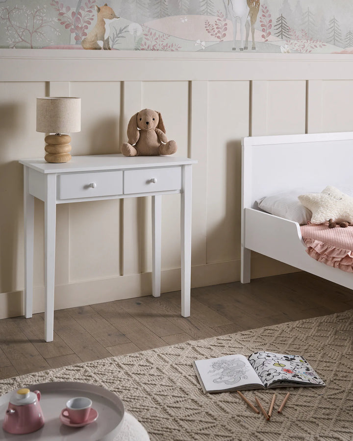 Children's bedroom with a white desk, bed, and toys on a wooden floor.