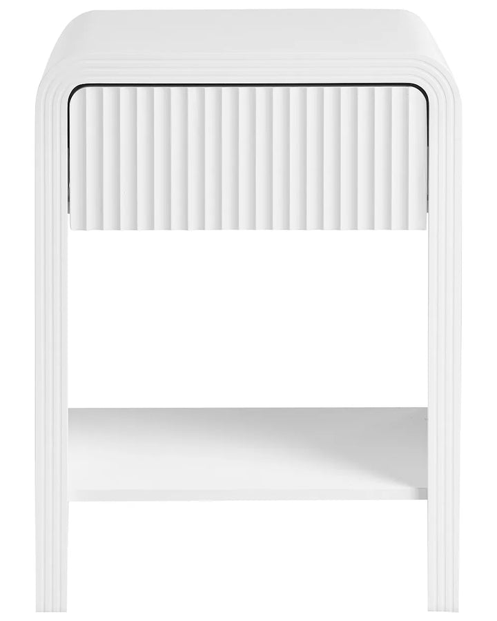 A modern white side table with a single ribbed drawer front, a curved outer frame, and a lower open shelf, shown against a plain white background.
