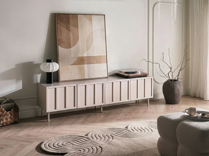 Modern living room with a long white cabinet, abstract painting, and decorative items.