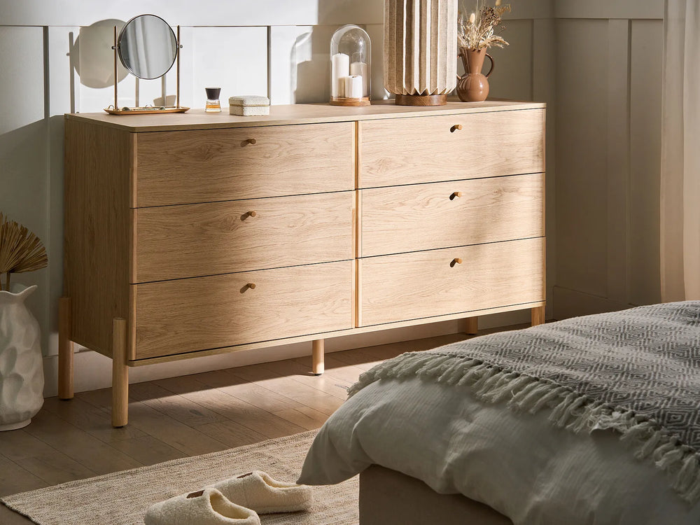 Wooden dresser with mirrors and decorative items in a bedroom setting