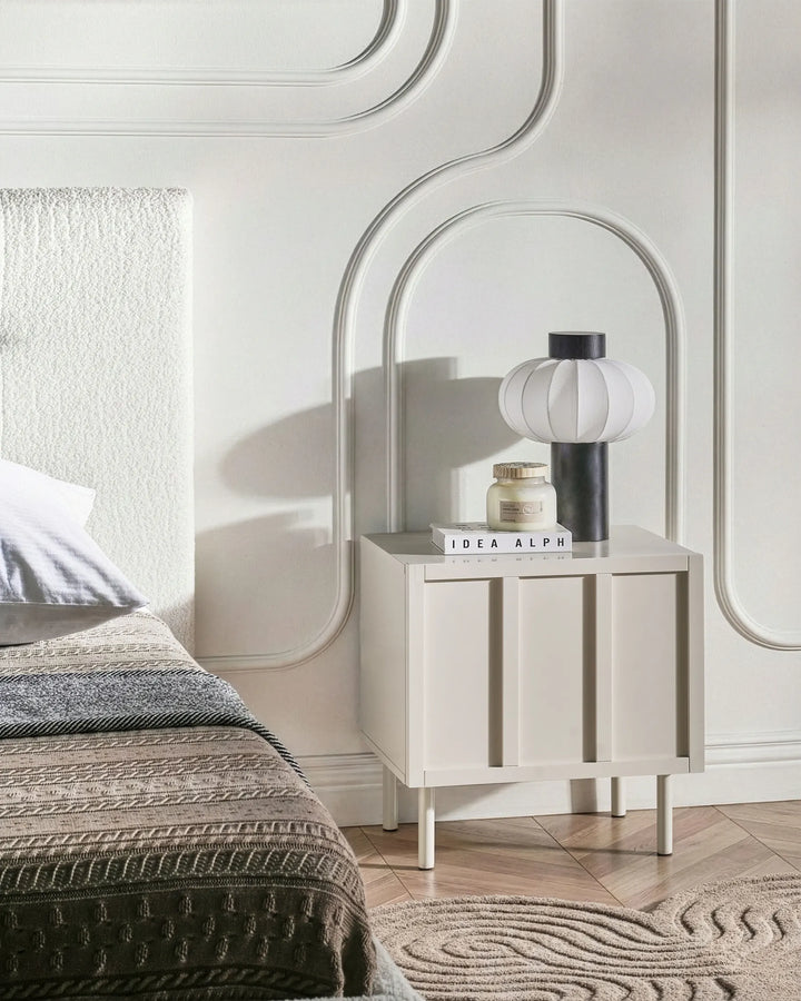 Neatly arranged bedroom with a nightstand, lamp, and decor items.