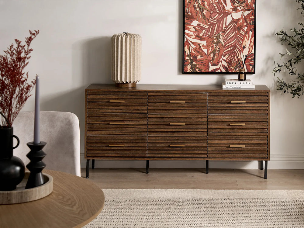 Wooden dresser in a living room with decor items and a painting.