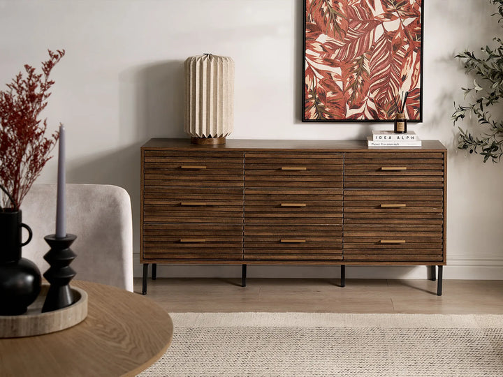 Wooden dresser in a living room with decor items and a painting.