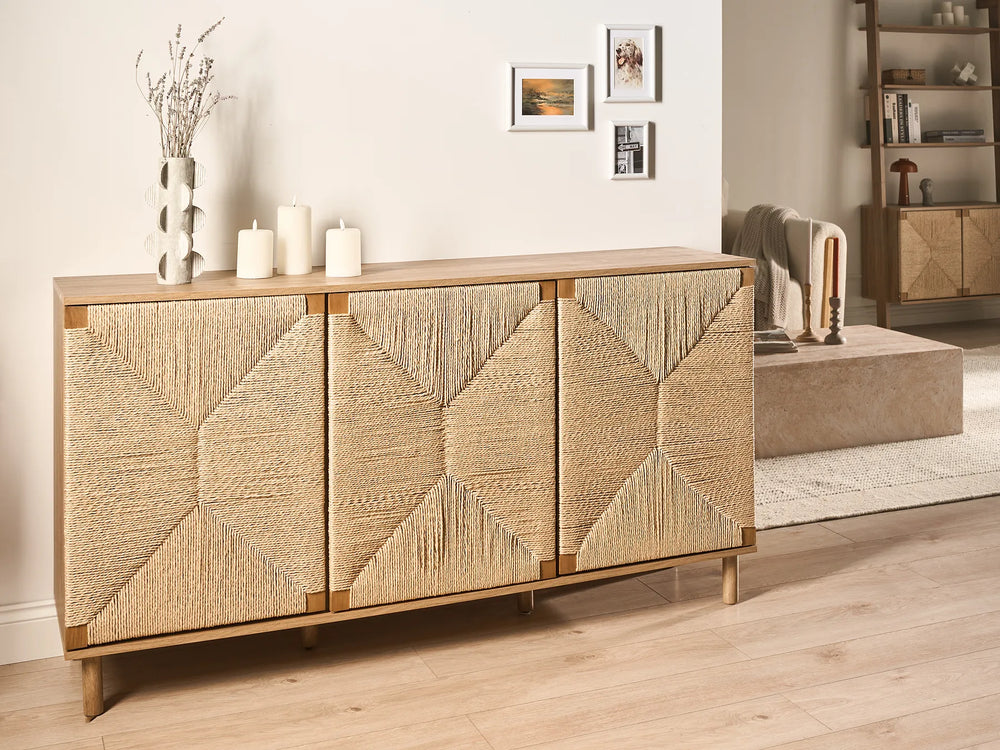 A mid-century modern sideboard cabinet with three doors featuring a geometric woven rattan pattern, finished in light natural wood with brass-toned metal frames, shown in a styled living room setting.