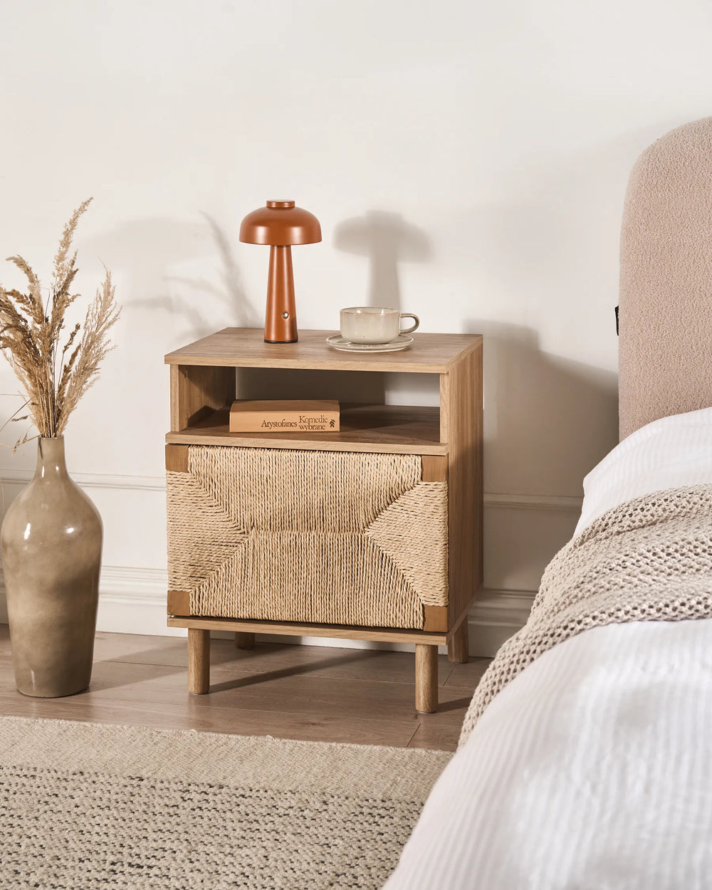 Wooden nightstand with woven design next to a bed in a bedroom setting.