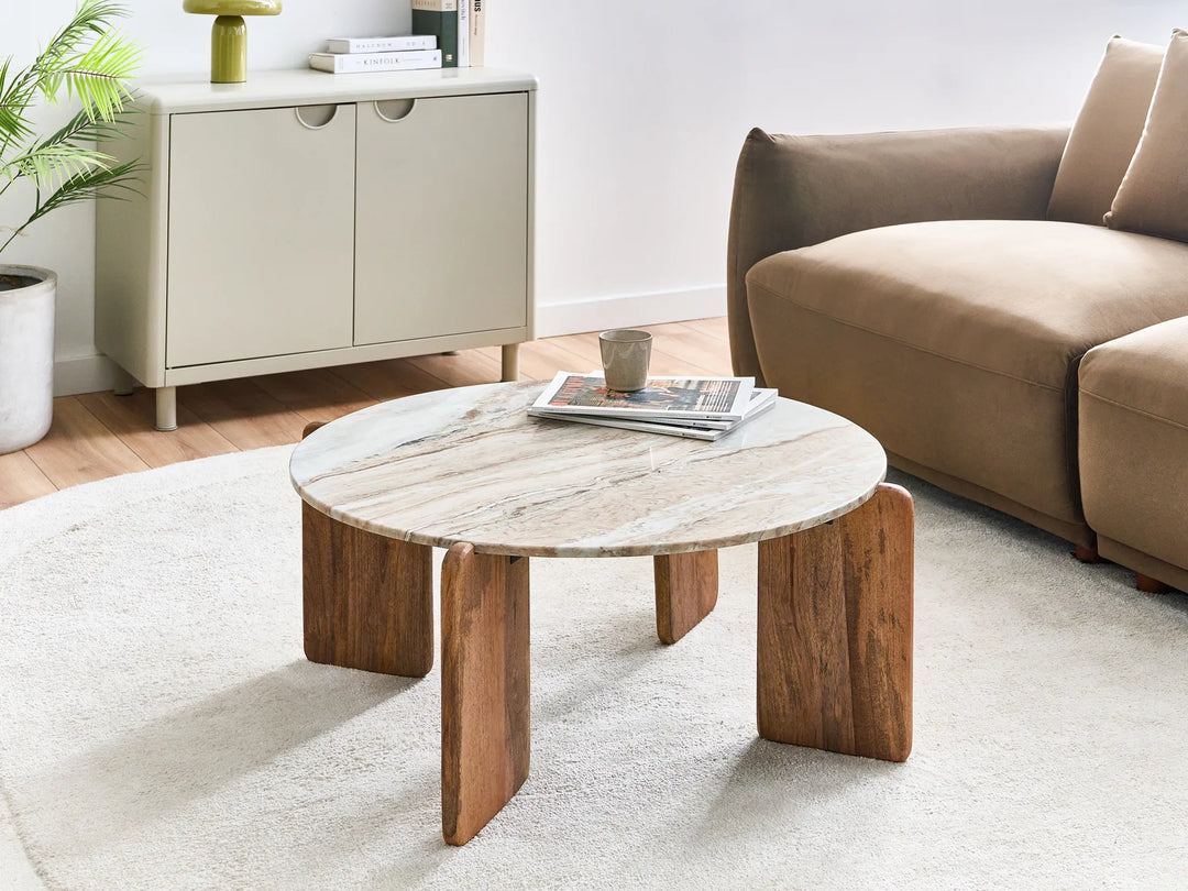 Round wooden coffee table in a living room with a beige sofa and sideboard.