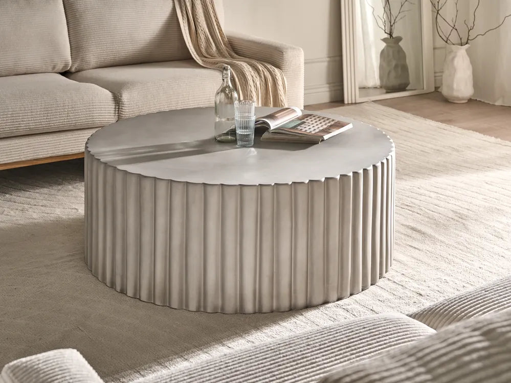 Round coffee table in a living room with a couch and decorative items.