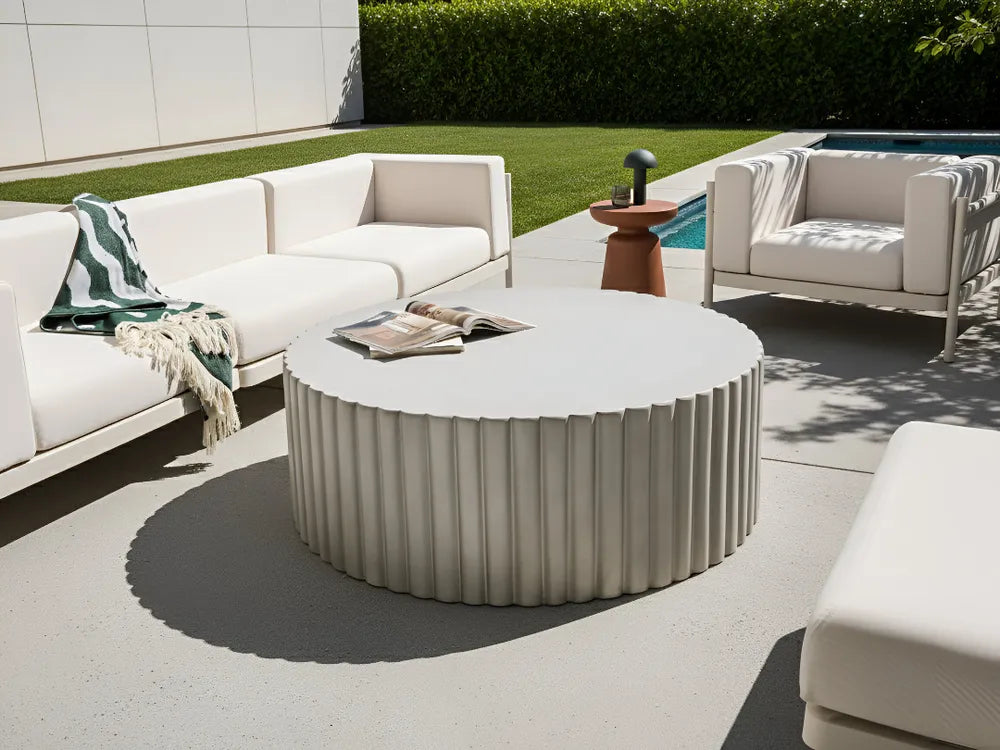 Outdoor patio setting with white furniture and a round table.