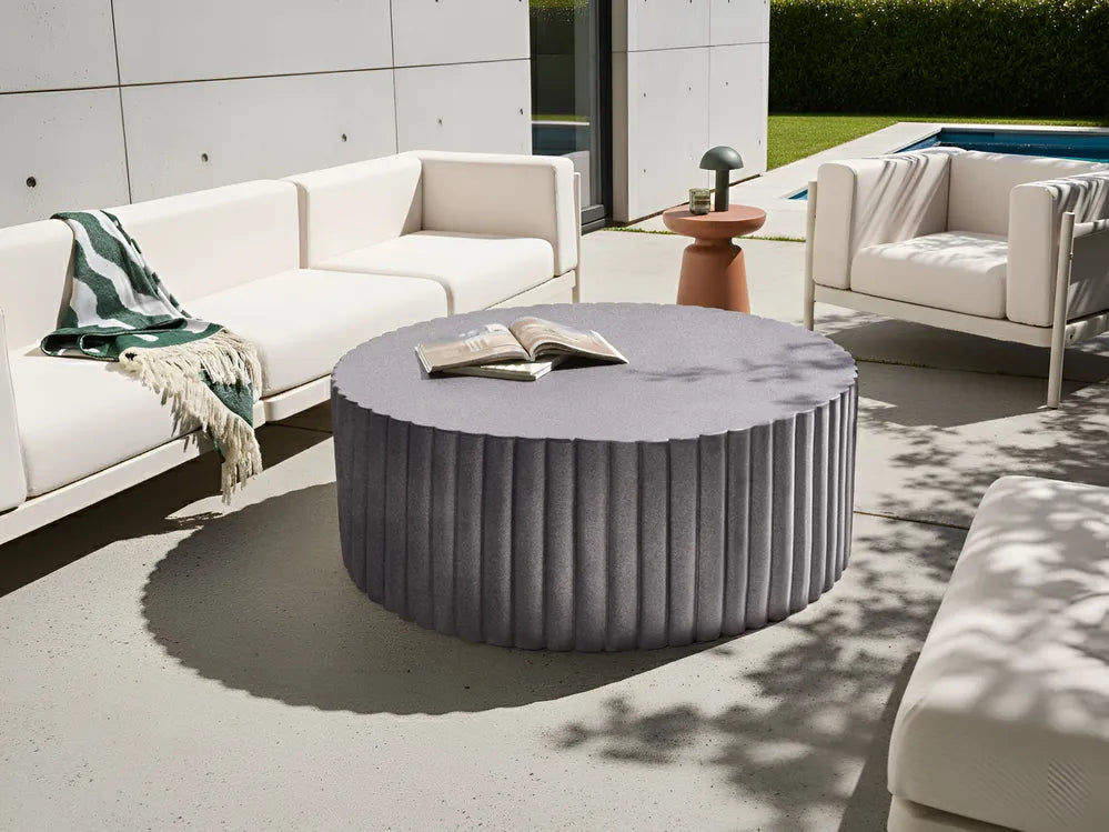 Outdoor patio setting with a round gray coffee table and white furniture.