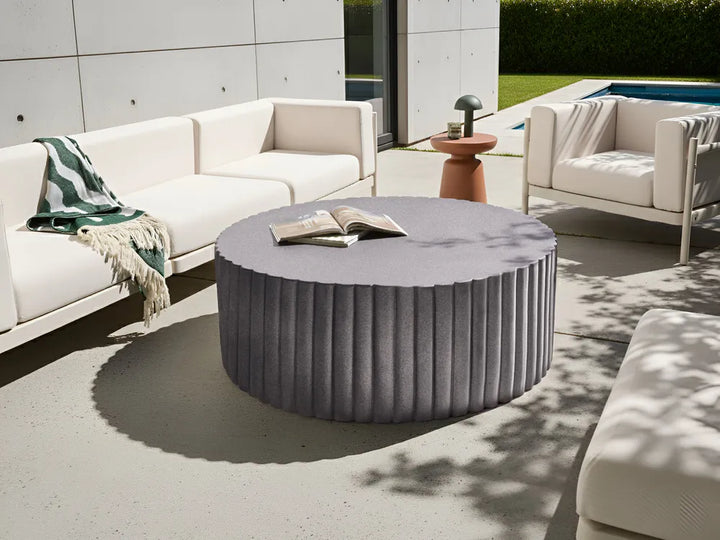 Outdoor patio setting with a round gray coffee table and white furniture.