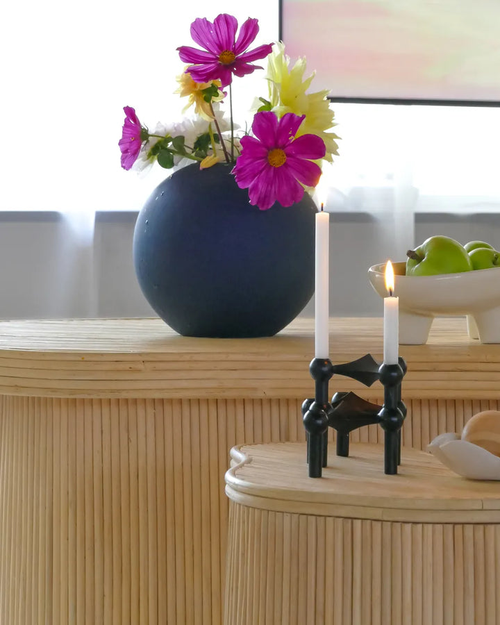 Decorative setup with a blue vase, pink flowers, and candle holders on a wooden surface.
