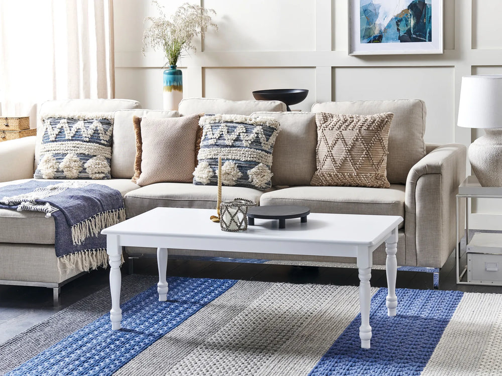 Living room with a beige sectional sofa, white coffee table, and decorative pillows.