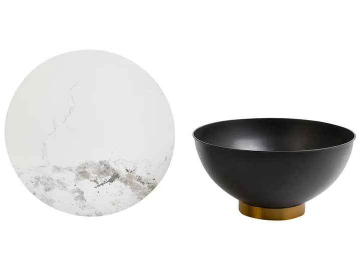 Black bowl with gold base next to a marble sphere on a white background