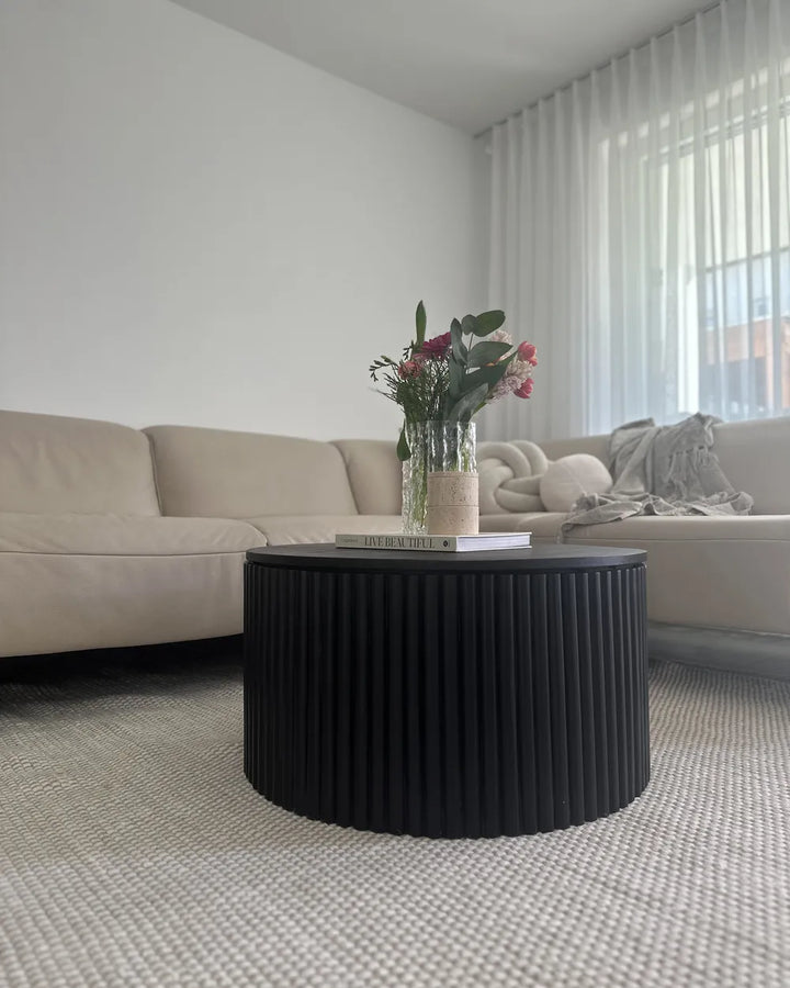 Modern living room with a black ribbed coffee table and beige sofa.