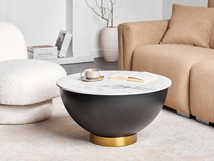 Modern coffee table with marble top and gold base in a living room setting.