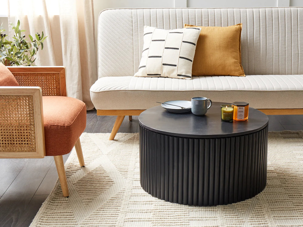 Living room with a black round coffee table, white sofa, and orange chair.