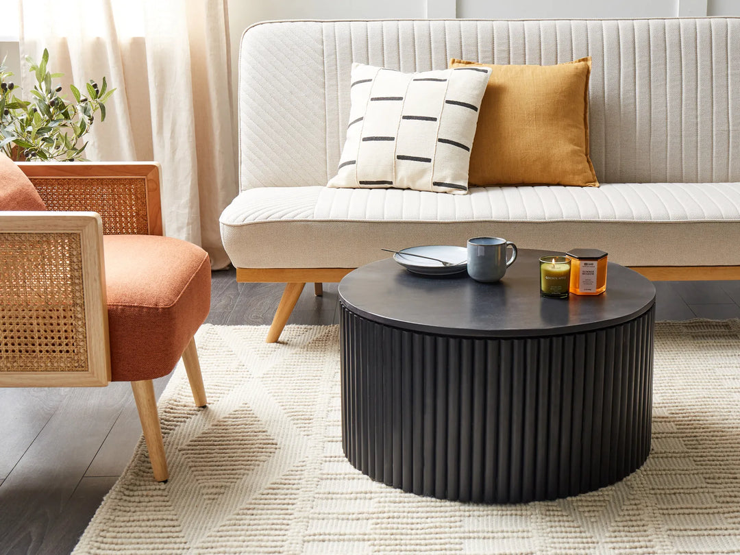 Living room with a black round coffee table, white sofa, and orange chair.