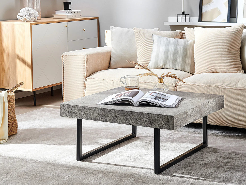 Modern living room with a beige sofa, concrete coffee table, and decorative items.