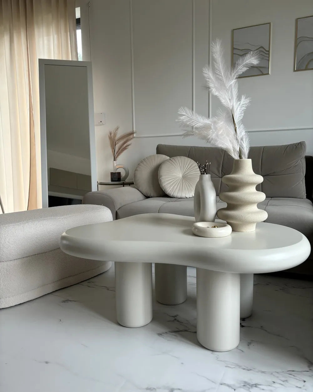 Modern living room with a white coffee table, gray sofa, and decorative elements.