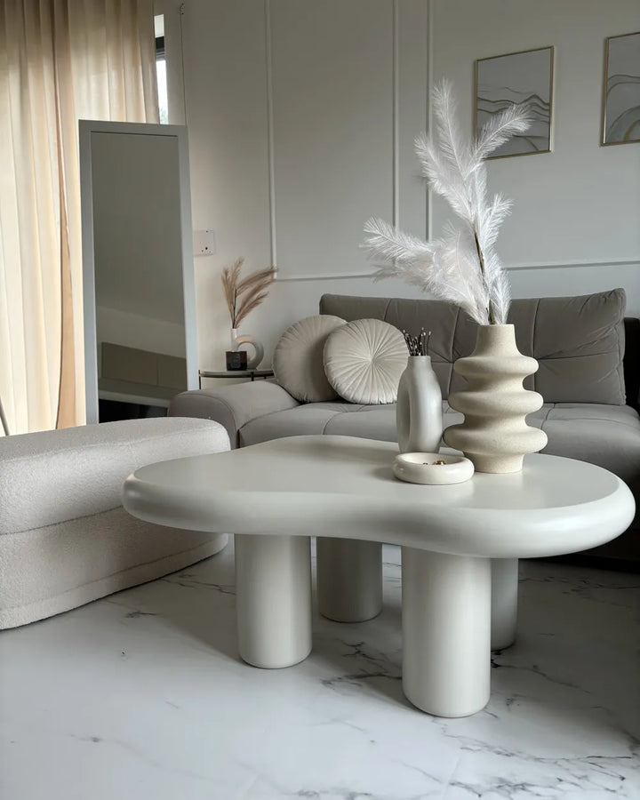 Modern living room with a white coffee table, gray sofa, and decorative elements.