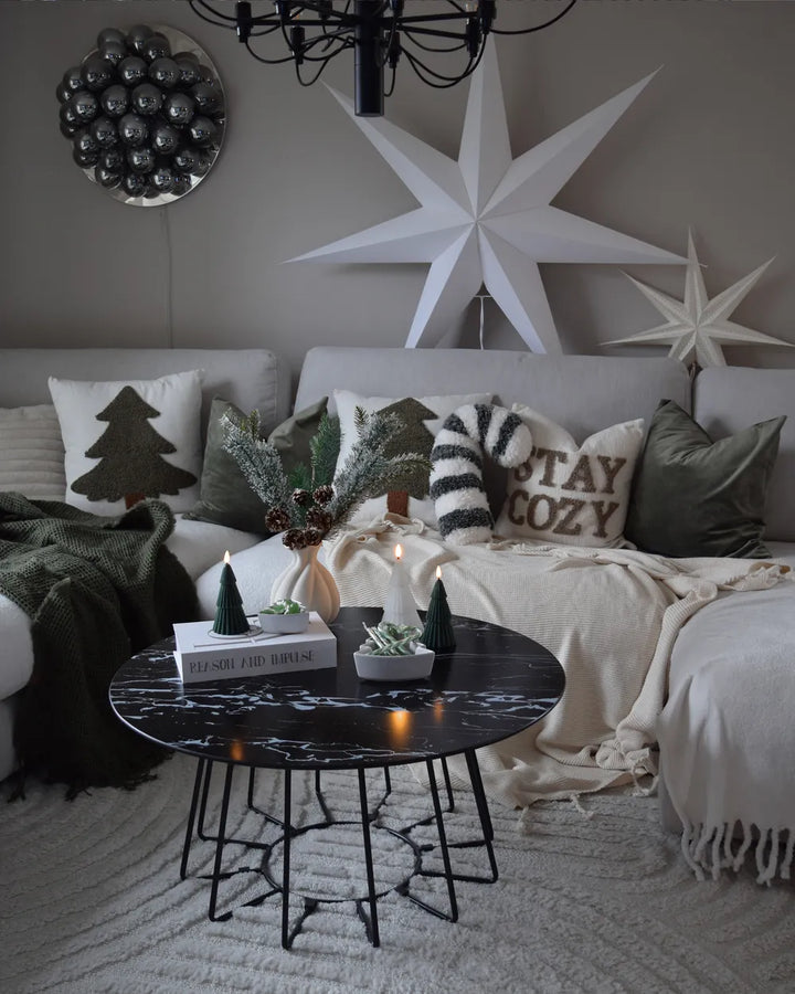 Cozy living room with decorative pillows, a star wall art piece, and a marble coffee table.