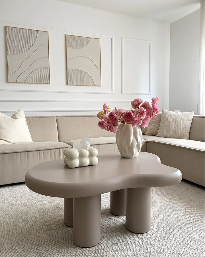 Modern living room with a beige sectional sofa, coffee table, and decorative elements.