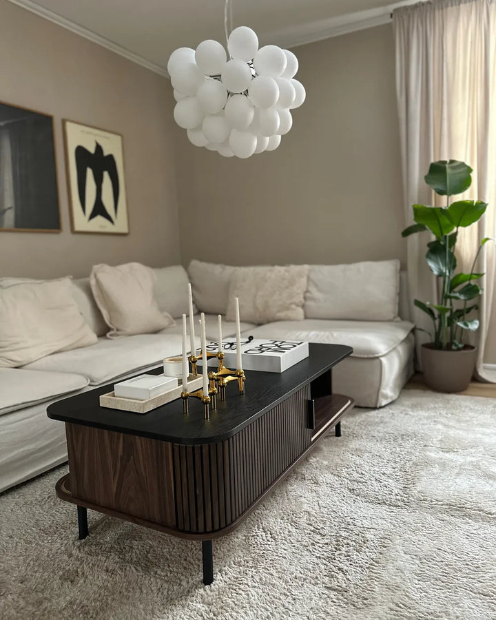 Modern living room with a white sofa, dark wood coffee table, and decorative items.