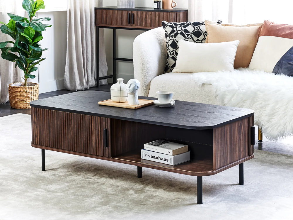 Wooden coffee table in a living room setting with a couch and decorative items.