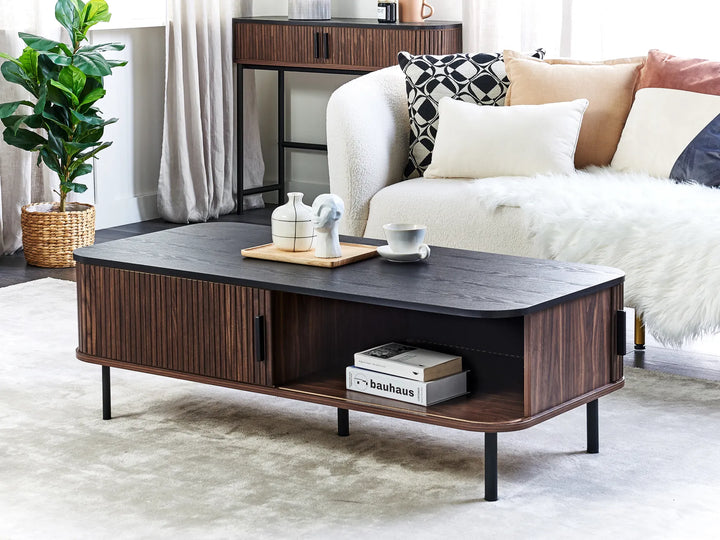 Wooden coffee table in a living room setting with a couch and decorative items.