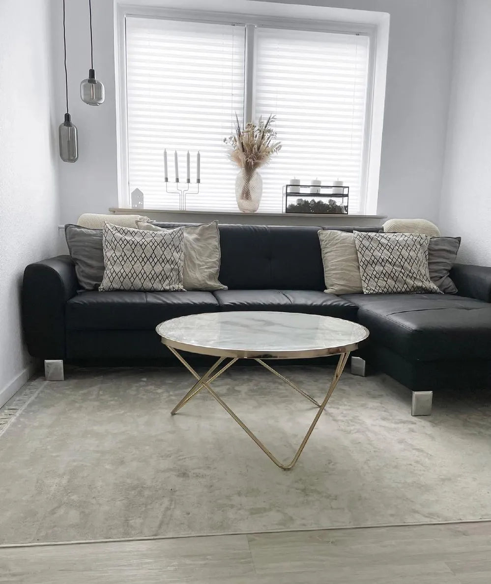 Modern living room with a black sofa, marble coffee table, and decorative pillows.