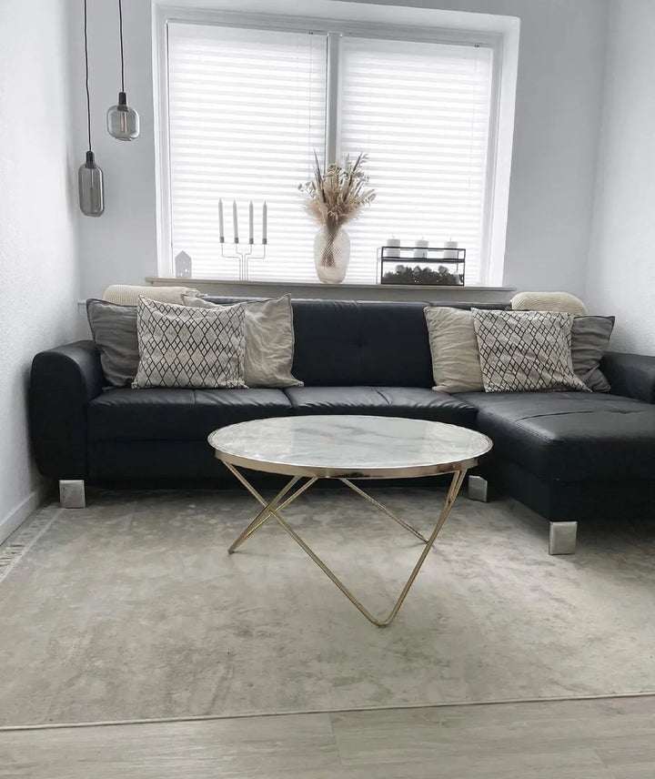 Modern living room with a black sofa, marble coffee table, and decorative pillows.