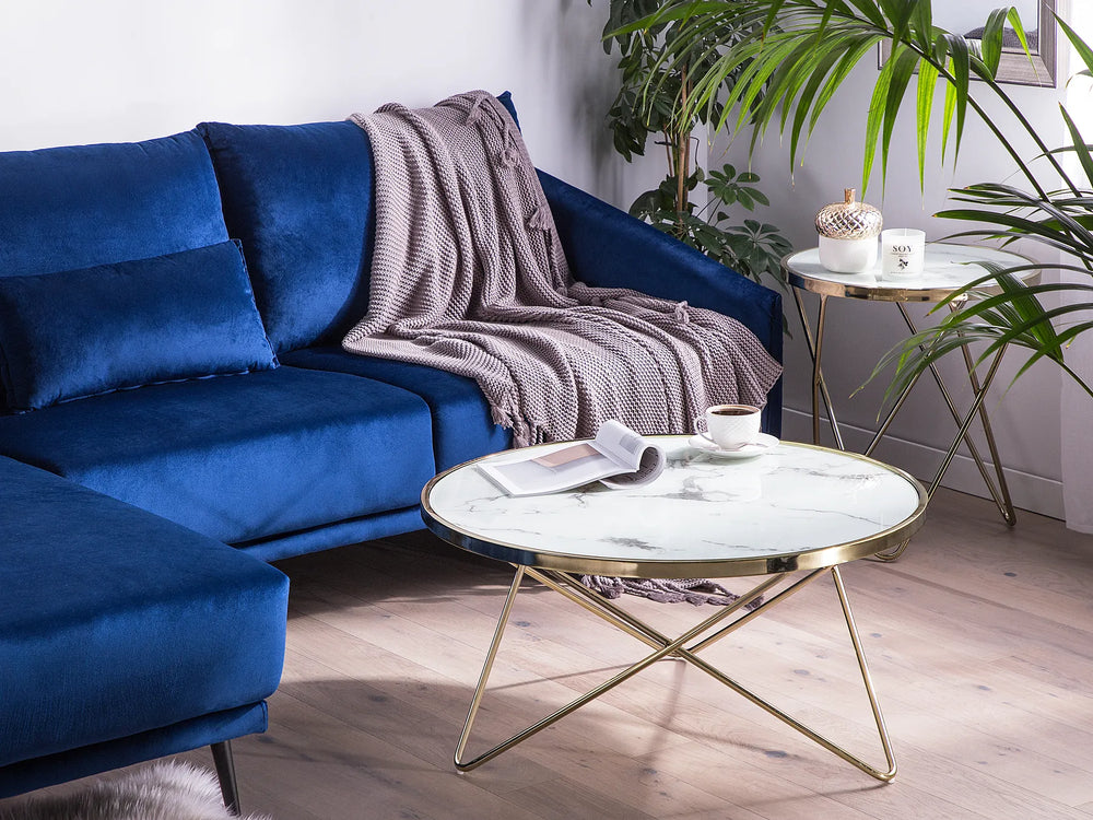 Blue sofa with a blanket in a living room setting with a coffee table and plants.