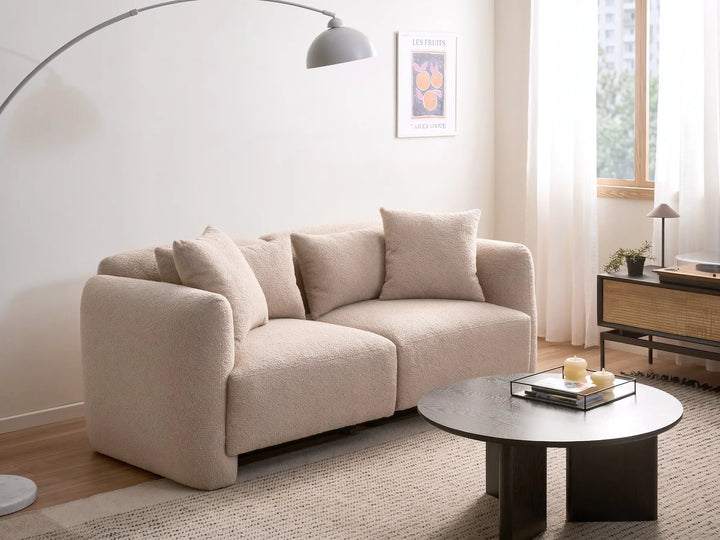 Beige sofa in a living room with a coffee table and decor items.