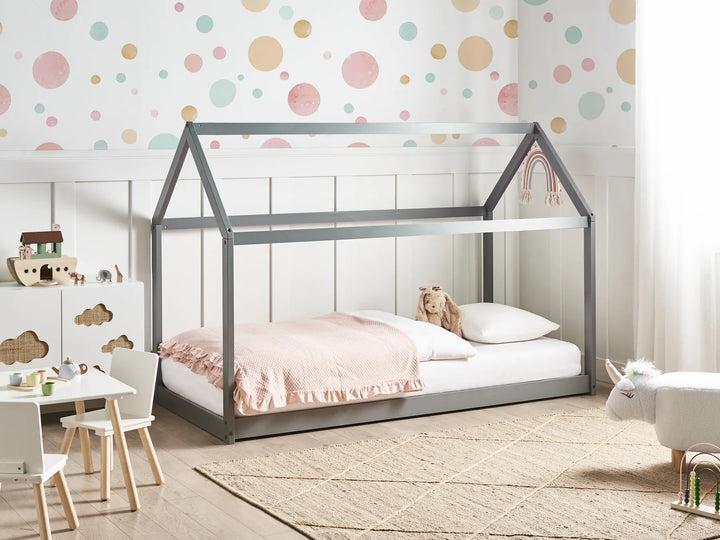 Children's room with a house-shaped bed, colorful polka dot wallpaper, and small table with chairs.
