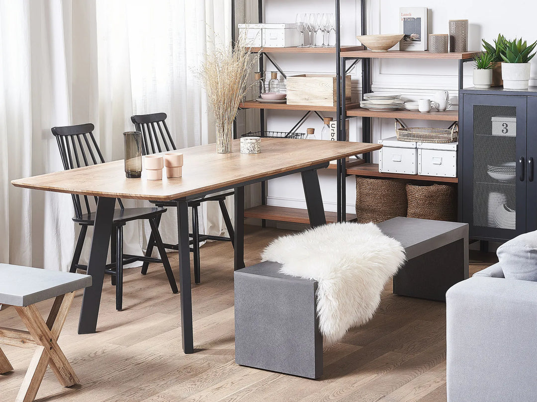 Modern living room with a wooden dining table and chairs, gray sofa, and bookshelf.
