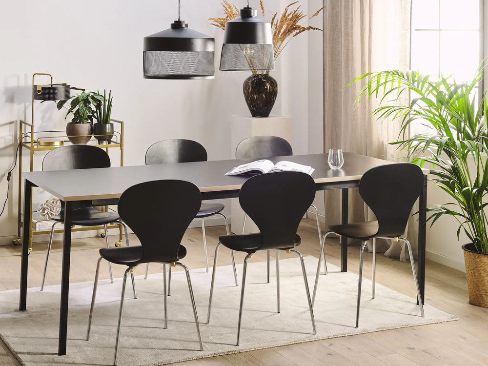 Modern dining room with a table and black chairs, plants, and decorative items.