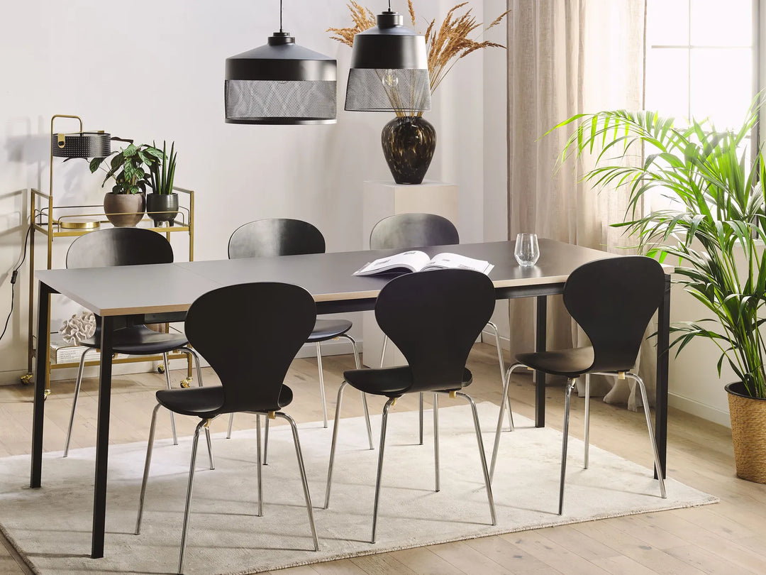 Modern dining room with a table and black chairs, plants, and decorative items.