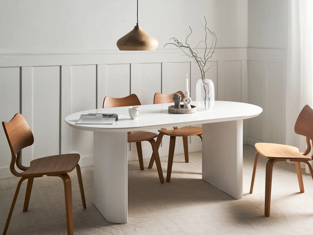 Modern dining room with a white oval table and wooden chairs.