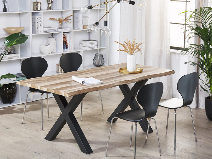 Dining room with a wooden table and black chairs in a modern interior setting.