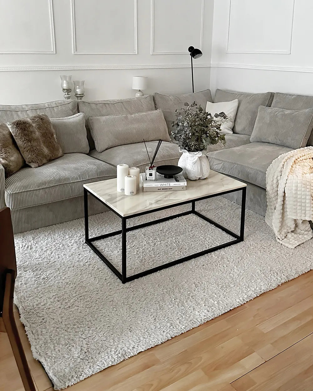 Modern living room with a gray sectional sofa, marble coffee table, and decorative items.