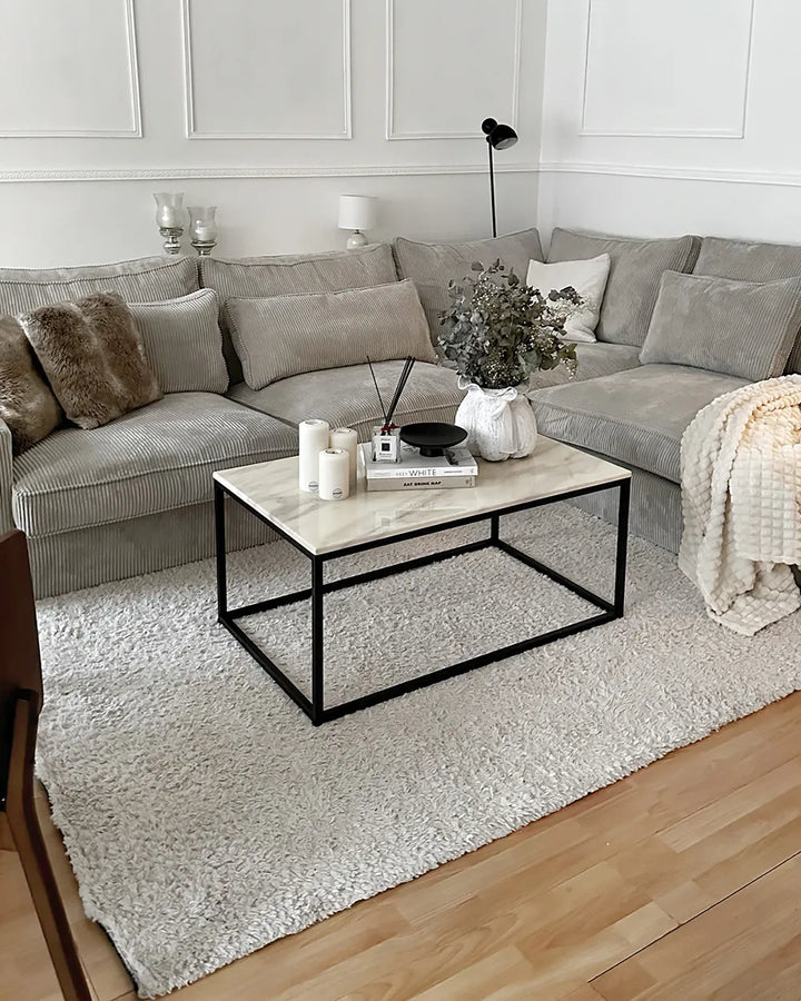 Modern living room with a gray sectional sofa, marble coffee table, and decorative items.